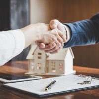 Real estate agent and customers shaking hands together celebrating finished contract after about home insurance and investment loan, handshake and successful deal.